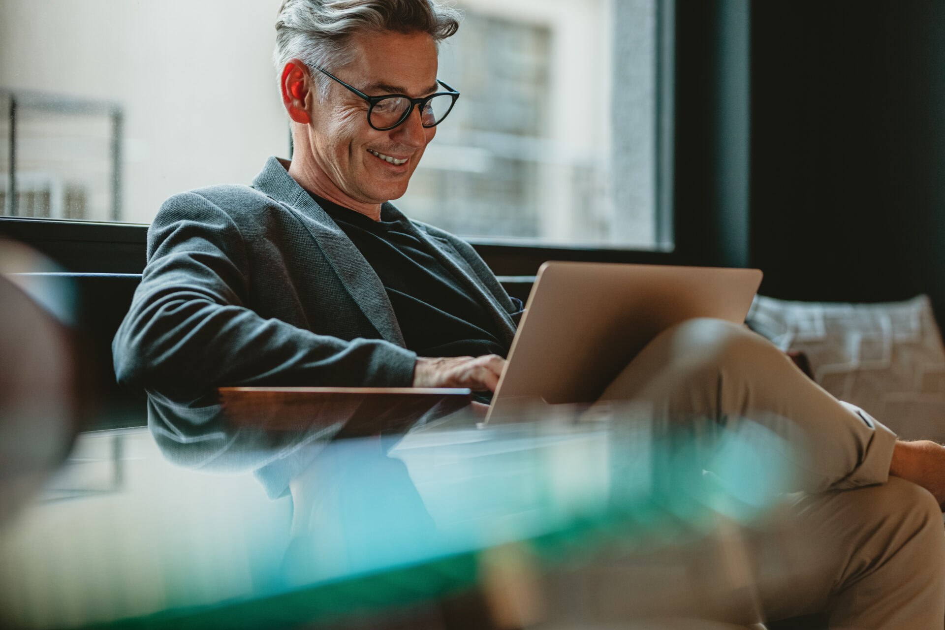 Smiling businessman sitting down in office on computer